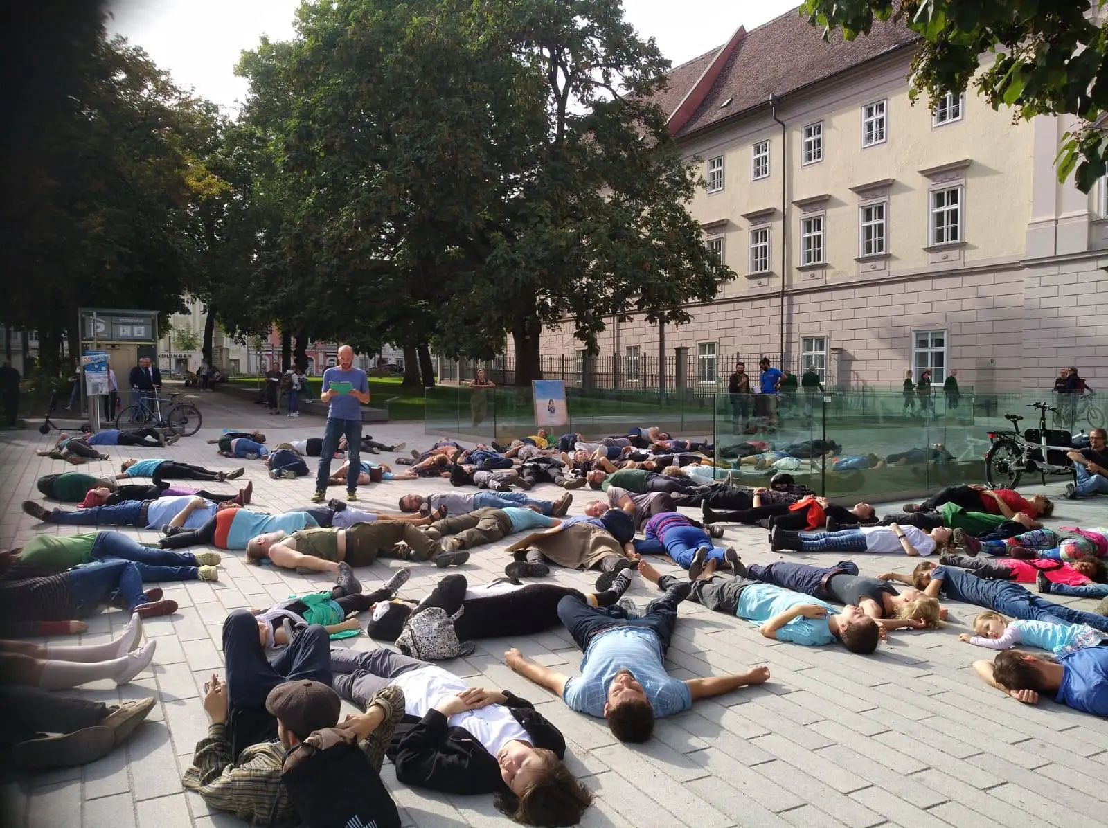 AktivistInnen und SympatisantInnen von XR Oberösterreich liegen vor dem Landhaus am Boden und symbolisieren damit das Artensterben und die Bedrohung durch die Klimakrise